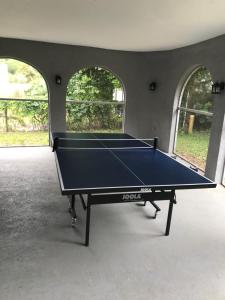 a ping pong table in a room with two windows at A home away from home in Orlando