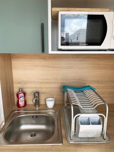 eine Küche mit einer Spüle und einer Mikrowelle in der Unterkunft 2 Pièces avec Balcon Plein Sud in Paris