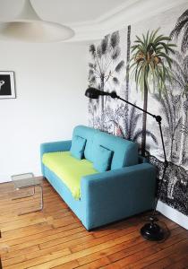 ein Wohnzimmer mit einem blauen Sofa und einer Lampe in der Unterkunft 2 Pièces avec Balcon Plein Sud in Paris