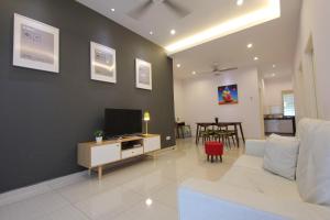 a living room with a white couch and a television at Saffron Stay Melaka in Malacca
