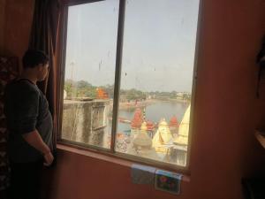 Kailash kuti Guest House في اوجاين: رجل ينظر من النافذة على منظر نهر
