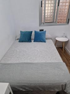 a bedroom with a large bed with blue pillows at Quarto com banheiro privado em apartamento familiar in Alicante