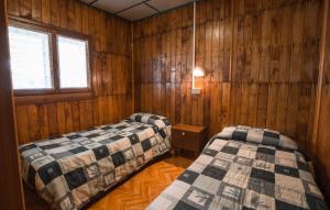 two beds in a room with wooden walls at Bungalow al Lago in Ledro