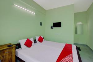 1 dormitorio con cama blanca y almohadas rojas en OYO Prasanth Holiday Inn, en Chegāt