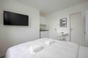 een witte slaapkamer met een bed en een flatscreen-tv aan de muur bij Urban Oasis with Queen Bed and View BE-42 in Zürich