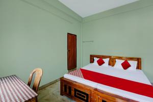 a bedroom with a bed and a table and a table and chair at OYO Prasanth Holiday Inn in Chekadi