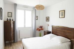 Habitación blanca con cama y ventana en Queyries - Appartement 2 chambres avec Parking en Burdeos