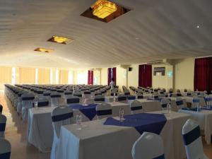 une grande salle de banquet avec des tables et des chaises blanches dans l'établissement Sai Rock Beach Hotel & Spa, à Bamburi