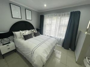 sypialnia z łóżkiem z białą pościelą i poduszkami w obiekcie Trendy, Comfortable 1 bedroom Apartments in Mthatha w mieście Mthatha