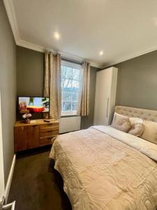a bedroom with a bed and a flat screen tv at Flat in the heart of Holland Park in London