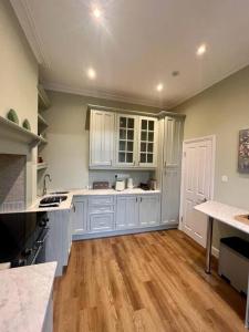 uma grande cozinha com armários brancos e pisos de madeira em Flat in the heart of Holland Park em Londres