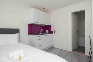 a white bedroom with a white bed and a purple kitchen at Urban Oasis with Queen Bed and View BE-29 in Zürich