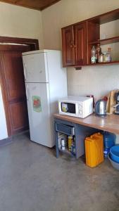 a kitchen with a white refrigerator and a microwave at COLIBRI VILLA 3 ROOMS in Gisenyi