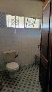 La salle de bains est pourvue de toilettes blanches et d'une fenêtre. dans l'établissement COLIBRI VILLA 3 ROOMS, à Gisenyi