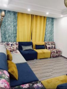 a living room with blue and yellow furniture and yellow curtains at Appartement moyen standing in Inezgane