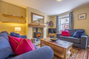 a living room with a blue couch and a fire place at Poppy Cottage H in Holt