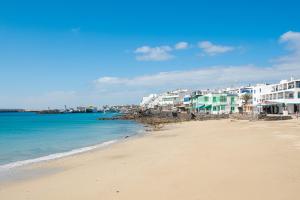 a beach with white buildings and the ocean at Blancazul Harbour View in Playa Blanca