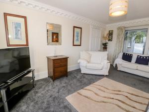 uma sala de estar com uma televisão e um sofá branco em 11 Glyn Garth Mews em Llandegfan