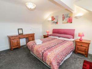 a bedroom with a bed and a dresser and a table at 11 Glyn Garth Mews in Llandegfan