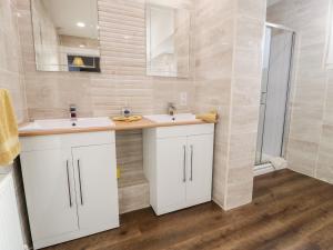 a bathroom with two sinks and a shower at 11 Glyn Garth Mews in Llandegfan