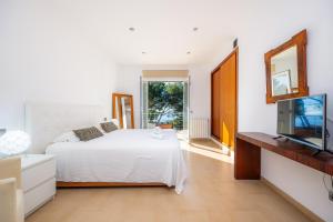 1 dormitorio con 1 cama blanca y TV en Villa Portals One, en Portals Nous