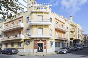 a yellow building with cars parked in front of it at Blue Peacock in Faro