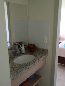 a bathroom counter with a sink and a mirror at Apartamento em Caldas Novas in Caldas Novas