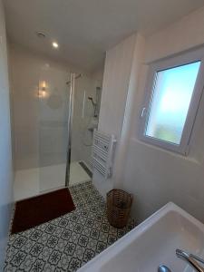 a bathroom with a shower and a tub and a window at Villa bord de mer avec piscine et jacuzzi in Pénestin