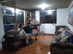 2 personas sentadas en una sala de estar con chimenea en Ilinizas Wasi Hospedaje-Restaurante, en Machachi