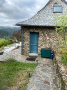 uma casa de pedra com uma porta azul numa colina em La tête dans les nuages em Le Fel