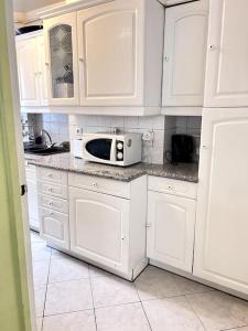 kuchnia z białymi szafkami i kuchenką mikrofalową w obiekcie Charmant appartement tout équipé avec 2 chambres w mieście Ivry-sur-Seine