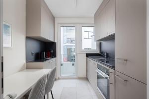 una cucina con mobili bianchi e una grande finestra di Grand Terrace Suite Elite 4,5BR BA52 a Zurigo