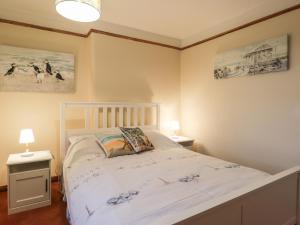 a bedroom with a white bed and two lamps at Rowan Tree House in Brora