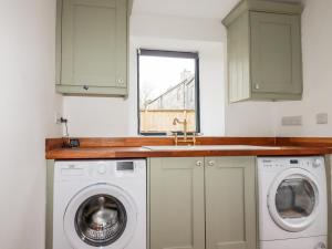 a kitchen with a washing machine and a sink at The Old Cattle Barn in Launceston