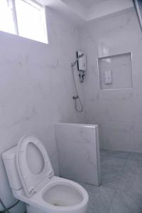 La salle de bains blanche est pourvue d'une douche et de toilettes. dans l'établissement Samed Seaside Resort - เสม็ด ซีไซด์ รีสอร์ท, à Ko Samet