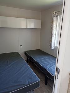 a small room with two beds and a window at Riva Bella chez Caraphou in Ouistreham