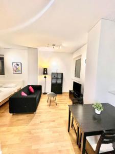 Una sala de estar con un sofá negro y una mesa. en Zurich City Dream Studio SH04L, en Zúrich