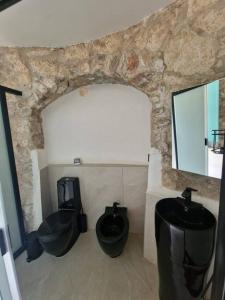 a bathroom with three black toilets and a stone wall at Torre del Principe suite in Salerno