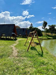 a wooden frame sitting in the grass next to a river at Lago Cristal Chalets in Los Santos