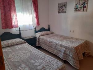 een slaapkamer met 2 bedden en een raam met rode gordijnen bij Apto. Dunas Playa in Isla Cristina