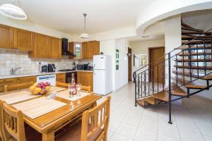 eine Küche mit einem Esstisch und einer Treppe in der Unterkunft Villa Wisteria Argaka in Argaka