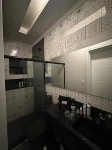 een badkamer met een wastafel en een glazen douche bij Casa Conteiner in Itaboraí