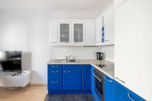 - une cuisine bleue avec des placards blancs et un évier dans l'établissement K&K Apartments Schönbrunn - Kingsize Bed & Netflix Self Check-In, à Vienne