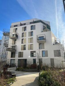 een hoog wit gebouw met balkons erop bij Cosy T2 au porte d’Orly-Rungis in Chevilly-Larue