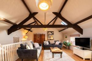 a living room with wooden ceilings and a tv at Stable Cottage in Teffont Magna