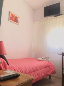 Schlafzimmer mit einem roten Bett und einem Schreibtisch mit Monitor in der Unterkunft Hotel Embassy in Miramar