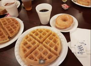 a table with two plates of waffles and a donut at Super 8 by Wyndham New Orleans in New Orleans