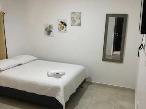 a bedroom with a white bed and a mirror at Hotel Samark Valledupar in Valledupar