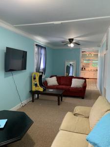 Il comprend un salon doté d'un canapé rouge et d'une télévision à écran plat. dans l'établissement Beachfront Cottage Best Location in Ocean View! cottage, à Norfolk