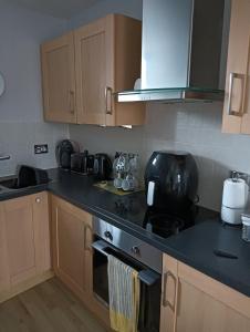 uma cozinha com armários de madeira e um balcão preto em Berwick upon Tweed flat em Berwick-Upon-Tweed